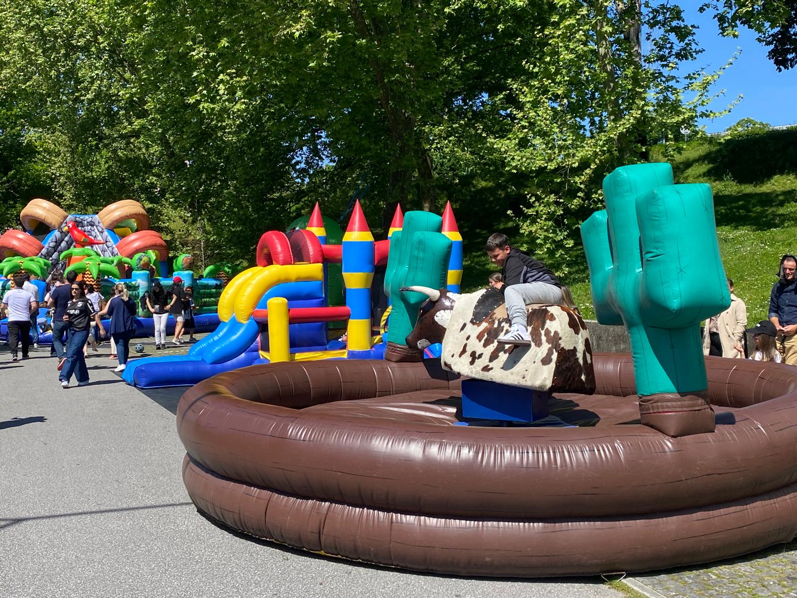 Criança no touro mecânico ao nível mais lento, numa festa num parque